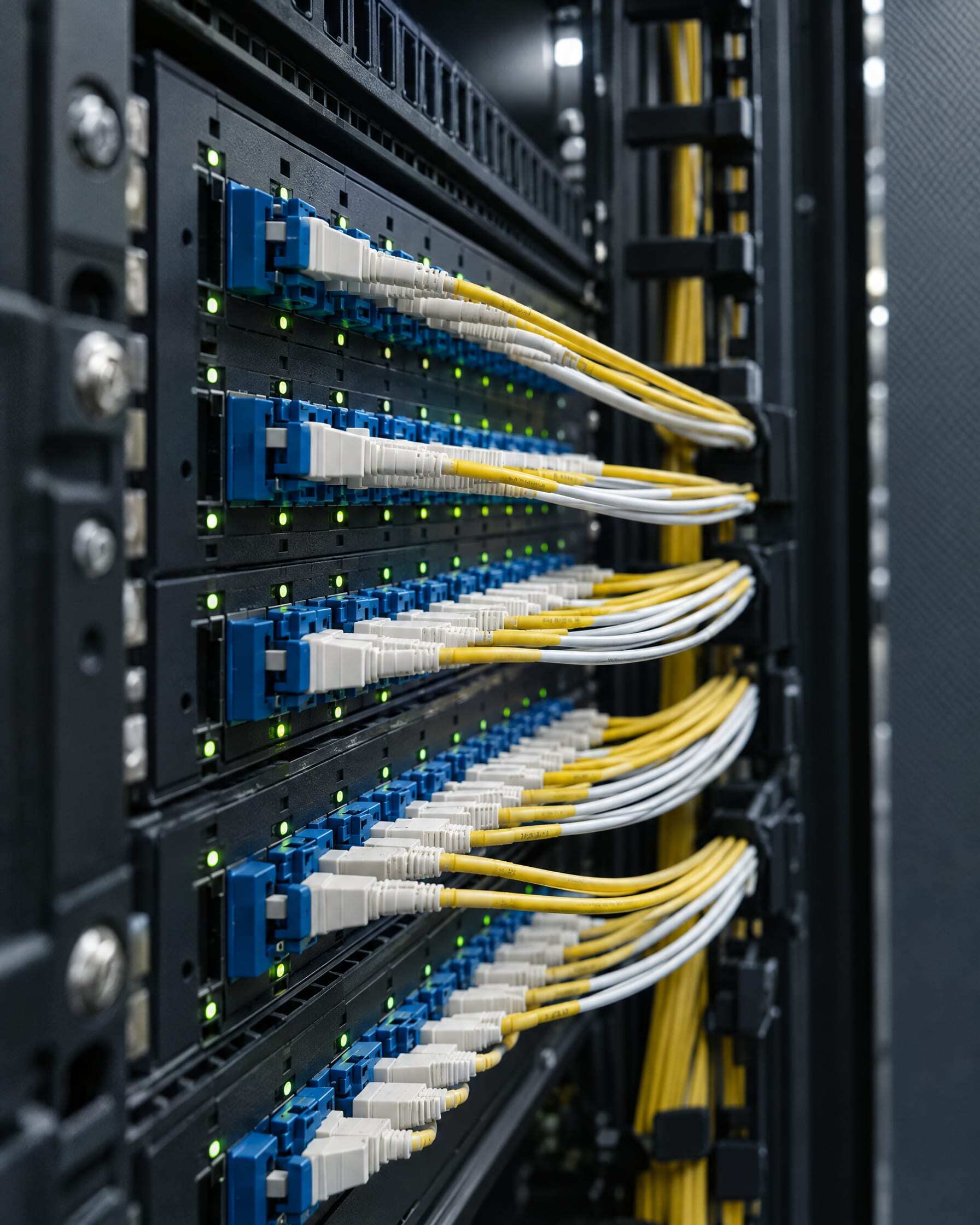 A fiber optic patch panel with rows of connectors and yellow and white cables